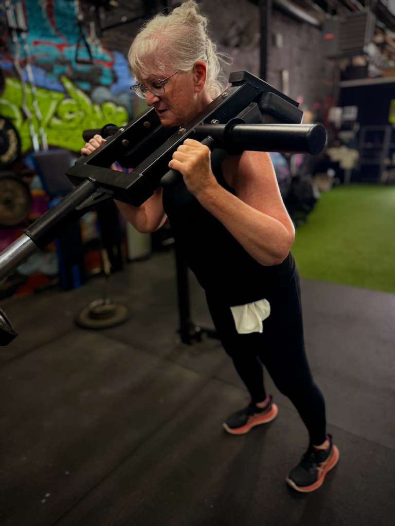 Client squatting with a safety squat bar