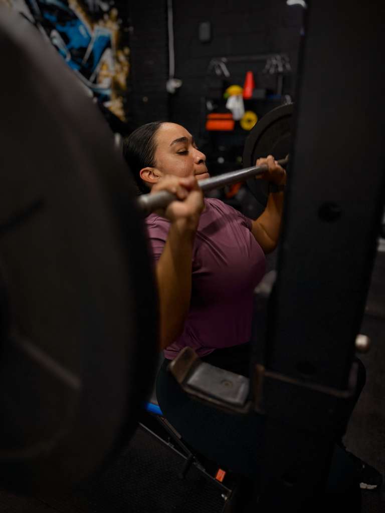 Client pressing a barbell in the squat rack