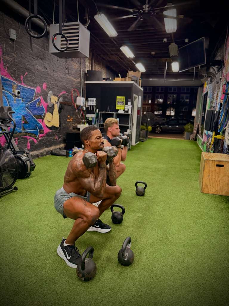 Clients doing kettlebell goblet squats in the training studio