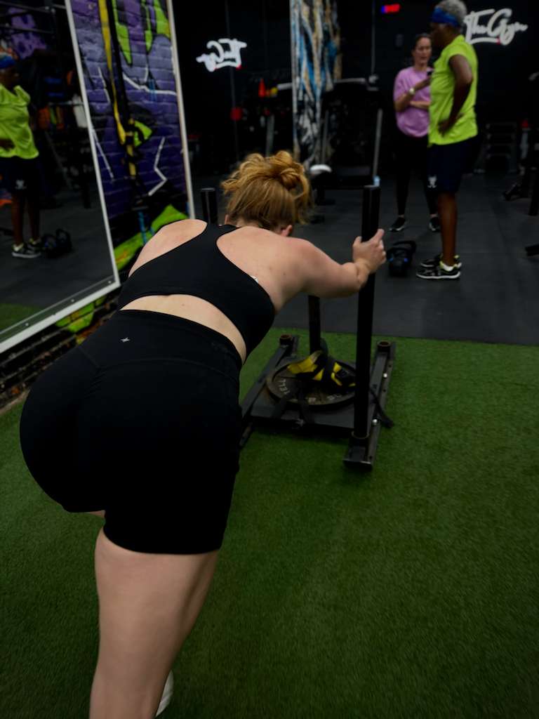 Client pushing a weighted sled on the turf