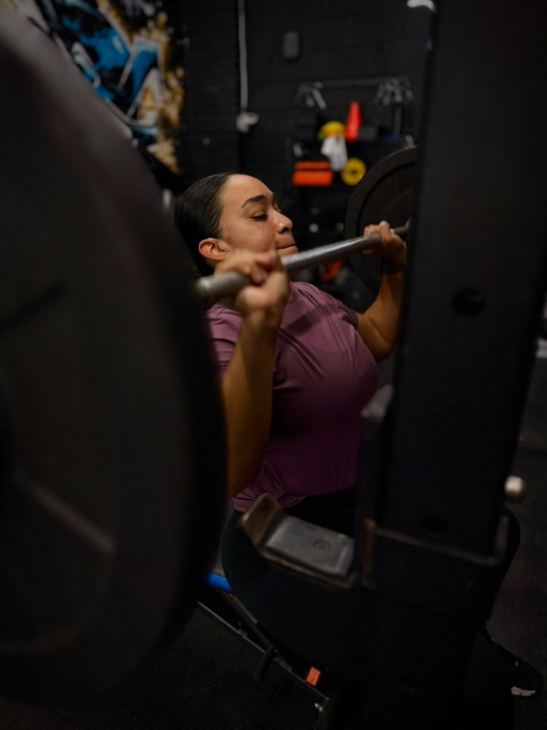 Client doing a barbell press in the squat rack